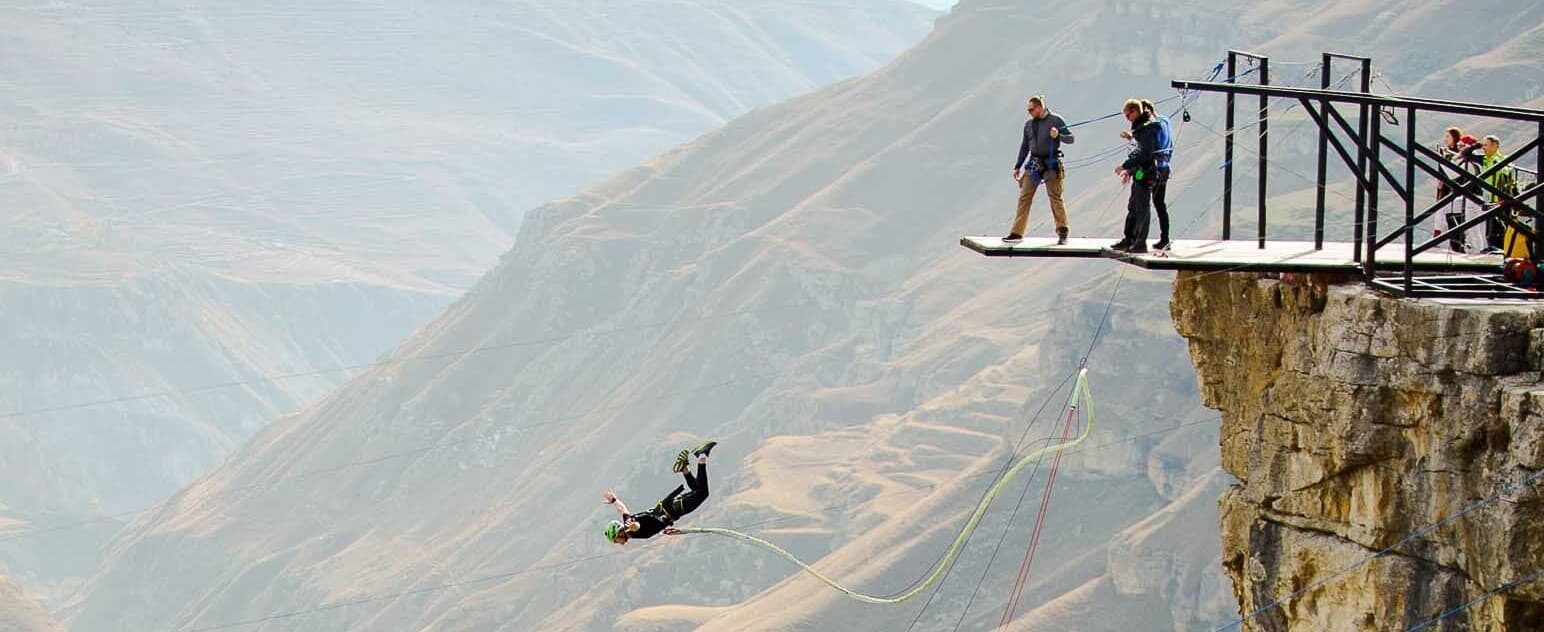 An individual taking a leap off a bungee platform, symbolizing the bold action needed for business transformation, part of the 12X Business Coaching program by Shop On Fire.