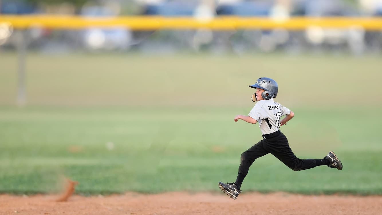 A young athlete sprinting on a baseball field, symbolizing the speed, skill, and determination of high-performing team members in Shop On Fire’s Leading A-Players coaching program.