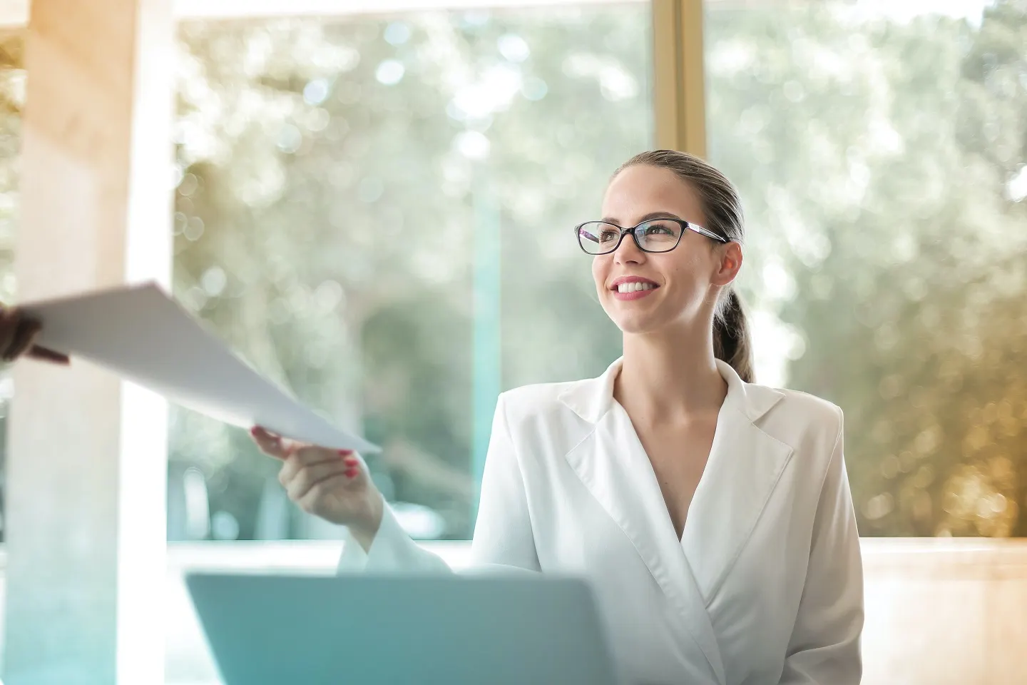 A confident woman in a white blazer receiving documents, representing delegation and leadership transition in Shop On Fire's Step Away CEO Program.