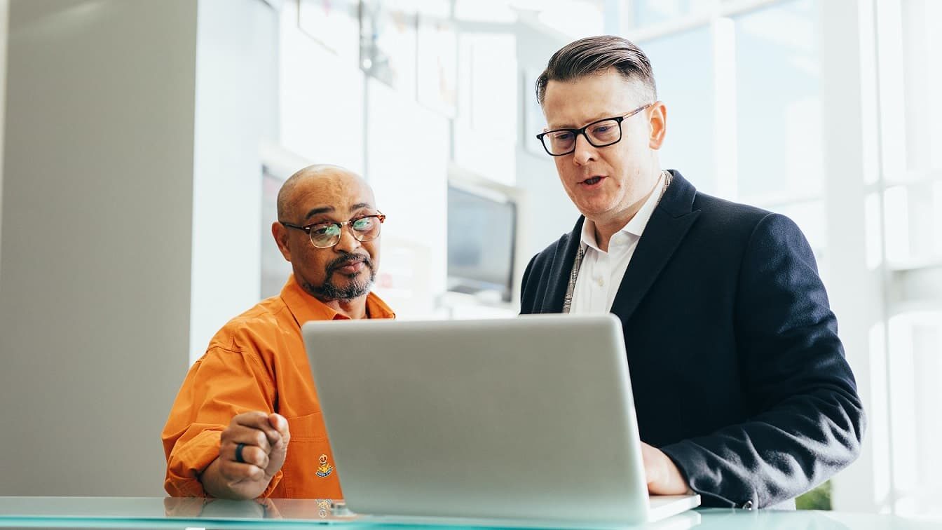 Two HVAC professionals reviewing a training module on a laptop during the 12X Technician Sales Training session. Focused on enhancing technician sales skills.