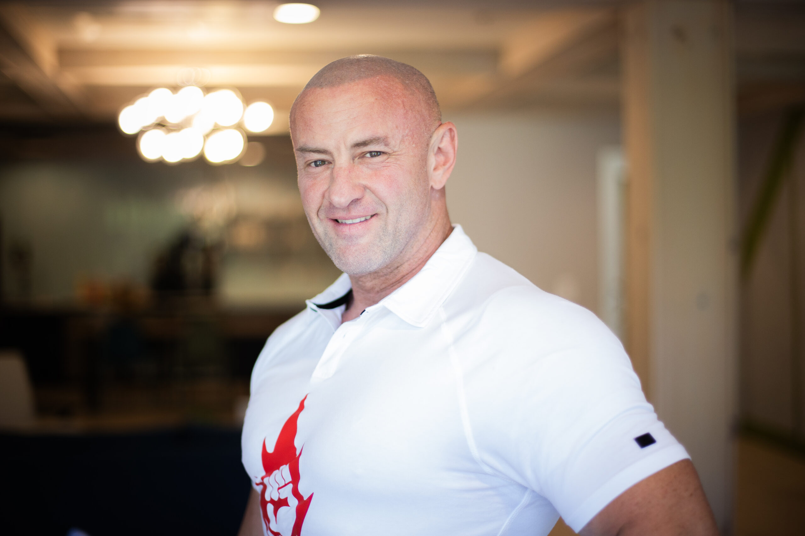 Jeremiah Webb, founder of Shop On Fire, wearing a branded shirt featuring the 'Fist of Fury' logo, a fist inside a flame with a lightning bolt beneath the left front palm, with a powerful and confident pose.